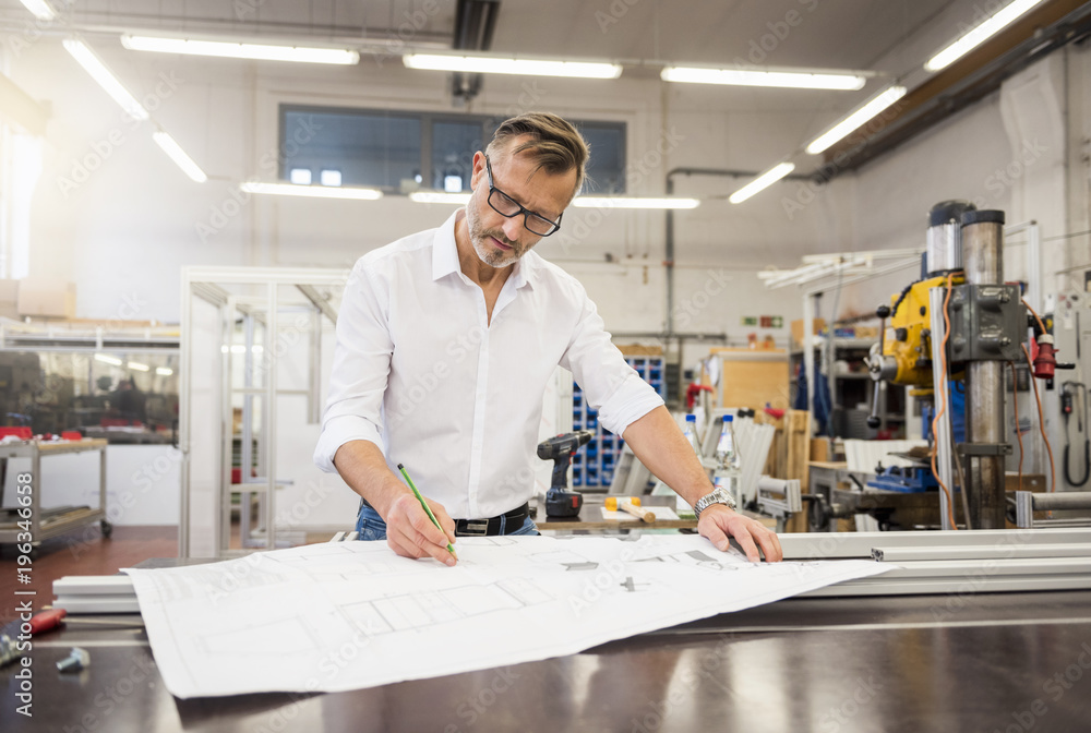 Mature businessman in factory working on plan Mature businessman in factory working on plan