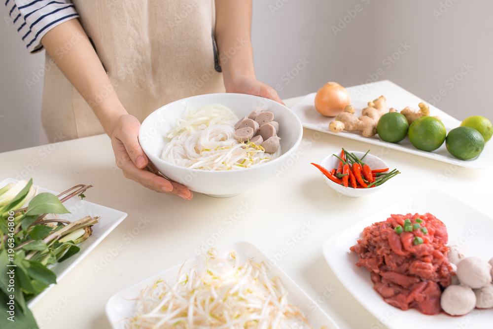 Female chef prepare traditional Vietnamese soup Pho bo with herbs, meat, rice noodles Female chef prepare traditional Vietnamese soup Pho bo with herbs, meat, rice noodles