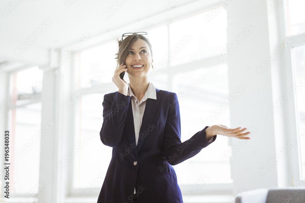 Smiling businesswoman on cell phone in bright room Smiling businesswoman on cell phone in bright room