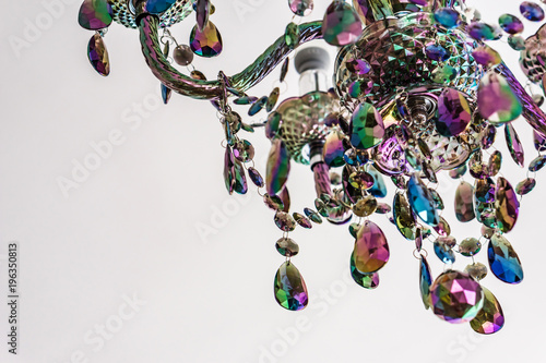 Closeup of a fragment of colored glass chandelier on white background. Color palette of green, purple, yellow and gold.