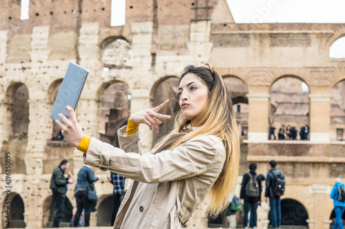 Photography Tourist with tablet doing self portrait at colosseum monument in Rome