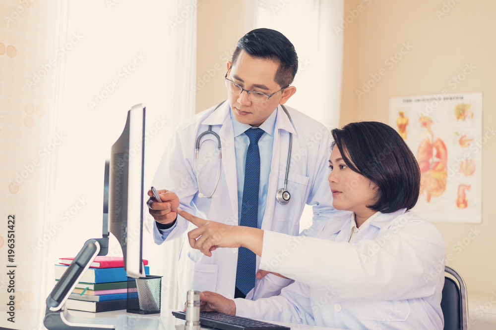 Doctors looking to hospital computer database, Male and female doctor examine of patient, They is being debated about the treatment the patients. health and medical concepts Doctors looking to hospital computer database, Male and female doctor examine of patient, They is being debated about the treatment the patients. health and medical concepts