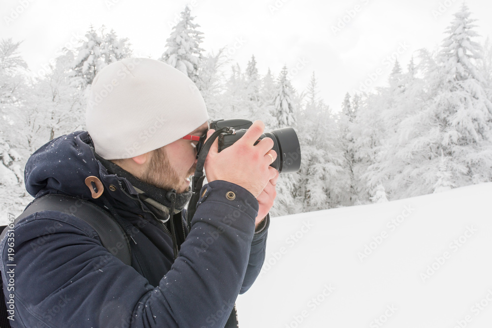 a man in a snowy winter forest with a backpack and a camera a man in a snowy winter forest with a backpack and a camera