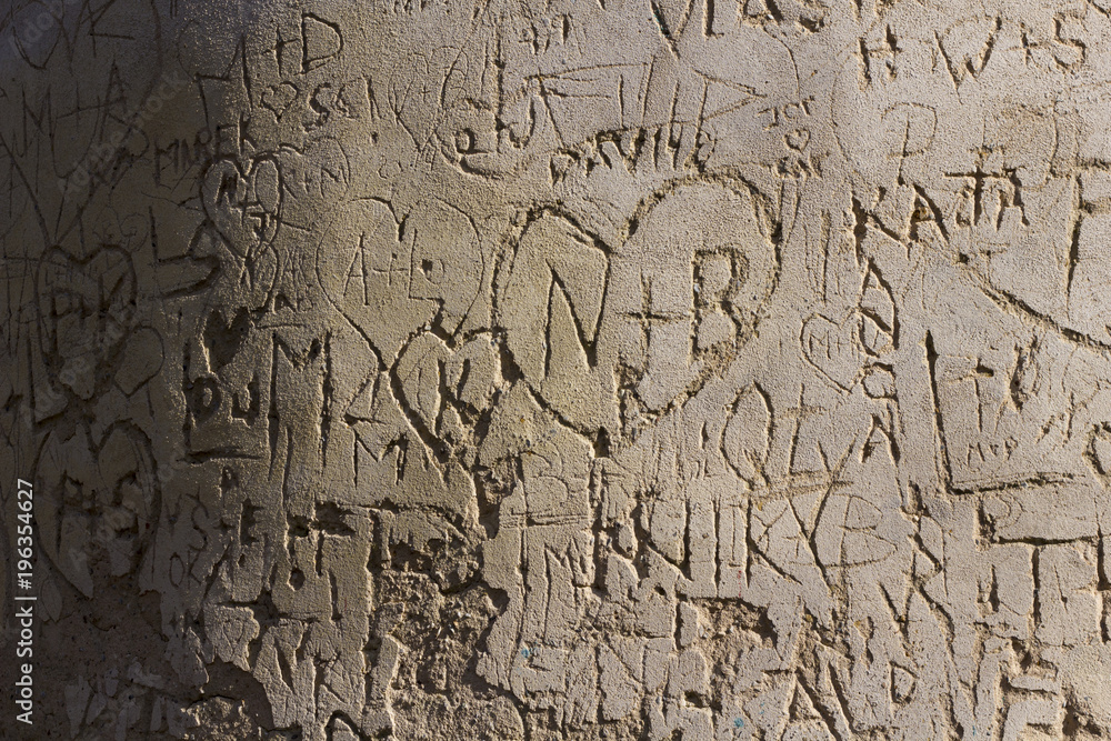 Lover's initials inside heart scratched on the old wall