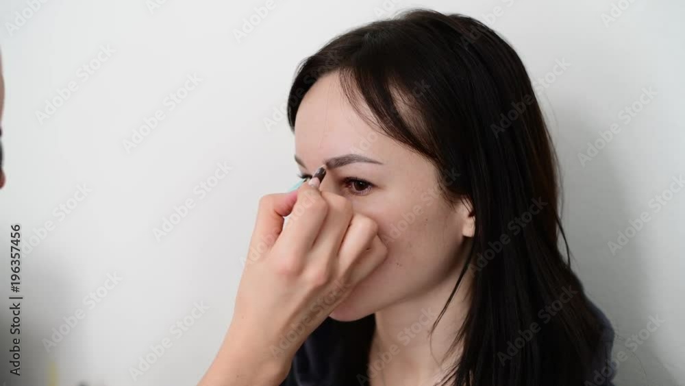 visagiste paints eyebrows young dark-haired girls visagiste paints eyebrows young dark-haired girls