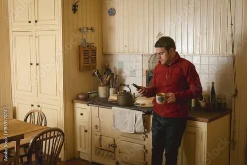 Man holding cordless telephone while having coffee at home
