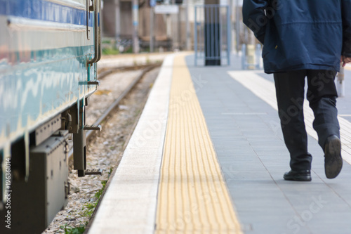 Horizontal View of a Man Walking In a Railway Station Next to a Train on Blur Background.