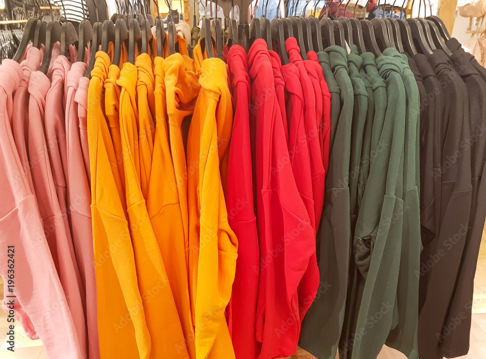 Fashion clothes on clothing rack,  bright colorful closet. color choice of trendy female wear on hangers in store closet or spring cleaning concept. Summer home wardrobe.