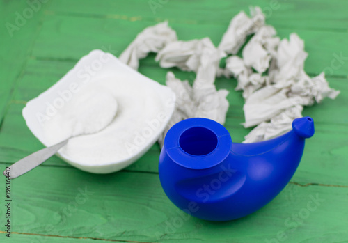 A device for washing the nose and crumpled toilet paper with snot in the background. photo