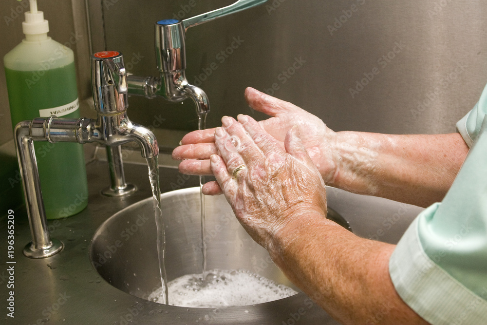 Healthcare professional washing hands in sink Healthcare professional washing hands in sink