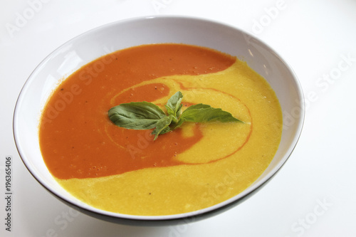 Bowl of yellow and orange soup with fresh herbs