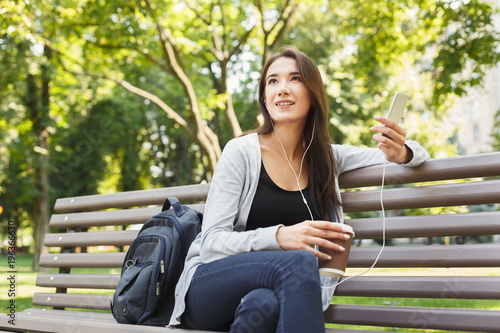 Student sitting in park and using smartphone