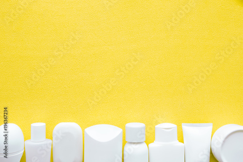Different, white beauty toiletries on yellow towel. Mock up for special offers as advertising. Cares about men's, women's and kids hair and body skin in summer. Empty place for text or logo. Flat lay.