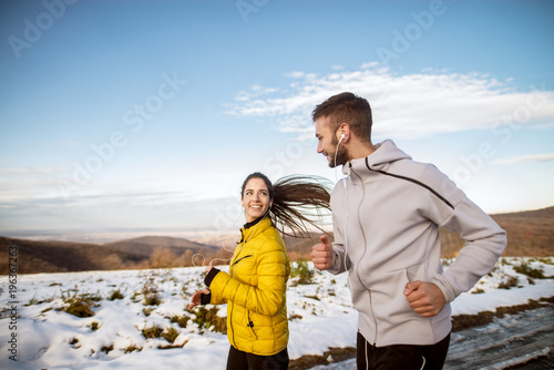 Attractive young couple running in the nature on a winter day.