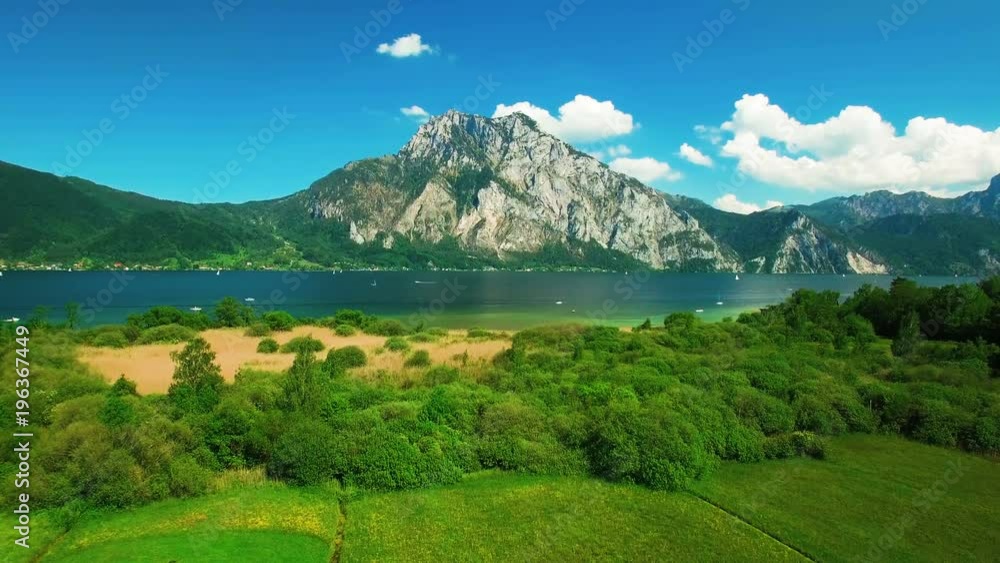 Aerial panoramic view of mountain next the lake with yachts. Aerial panoramic view with clouds and blue sky in Austria Aerial panoramic view of mountain next the lake with yachts. Aerial panoramic view with clouds and blue sky in Austria