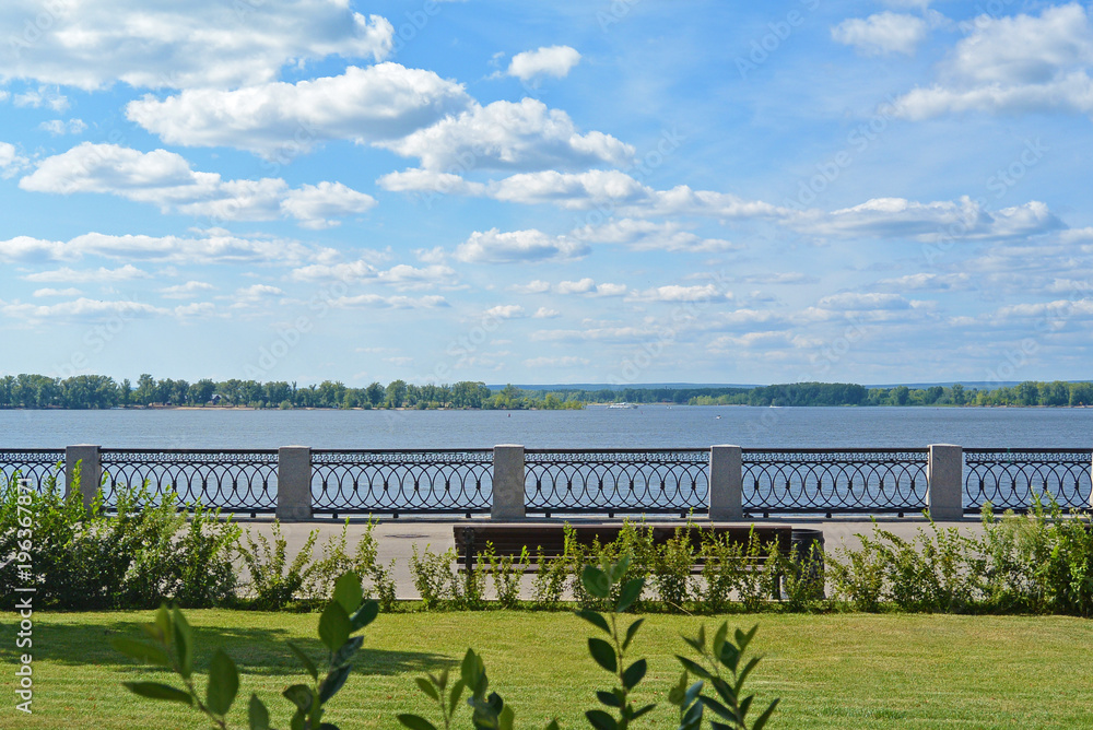 Front view on the Volga quay of the Samara. Green grass on city embankment, beautiful sky with cumulus clouds on sunny summer day