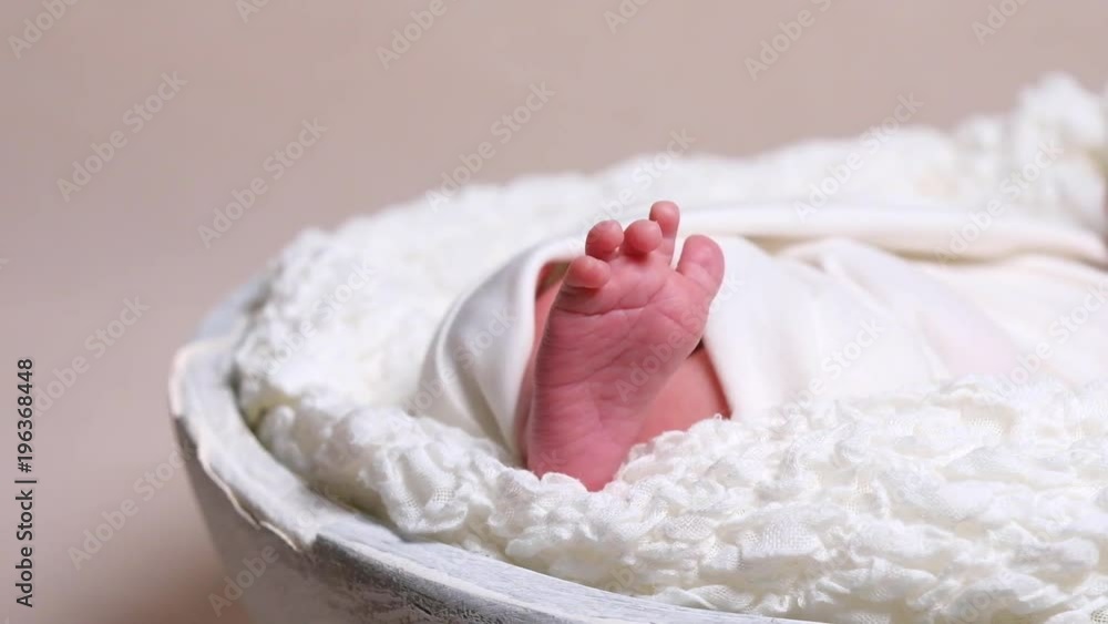 Small bare feet of newborn baby wrapped in warm white blanket Small bare feet of newborn baby wrapped in warm white blanket