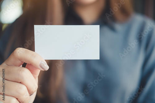 A business woman holding and showing empty business card in office