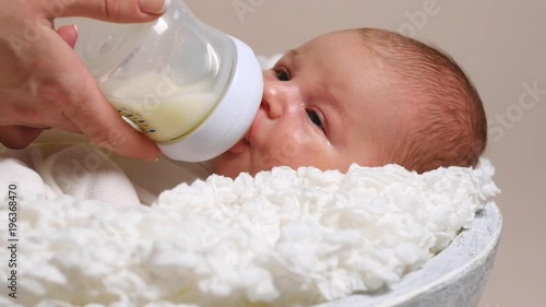 Mother feeding her little boy from bottle. Cute baby drinking milk from baby bottle