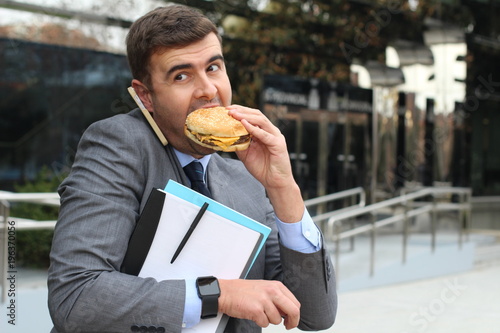 Fényképezés Busy businessman walking, calling and having lunch simultaneously