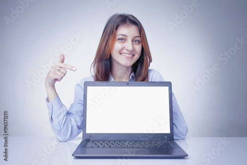 Happy young business woman showing finger on laptop screen