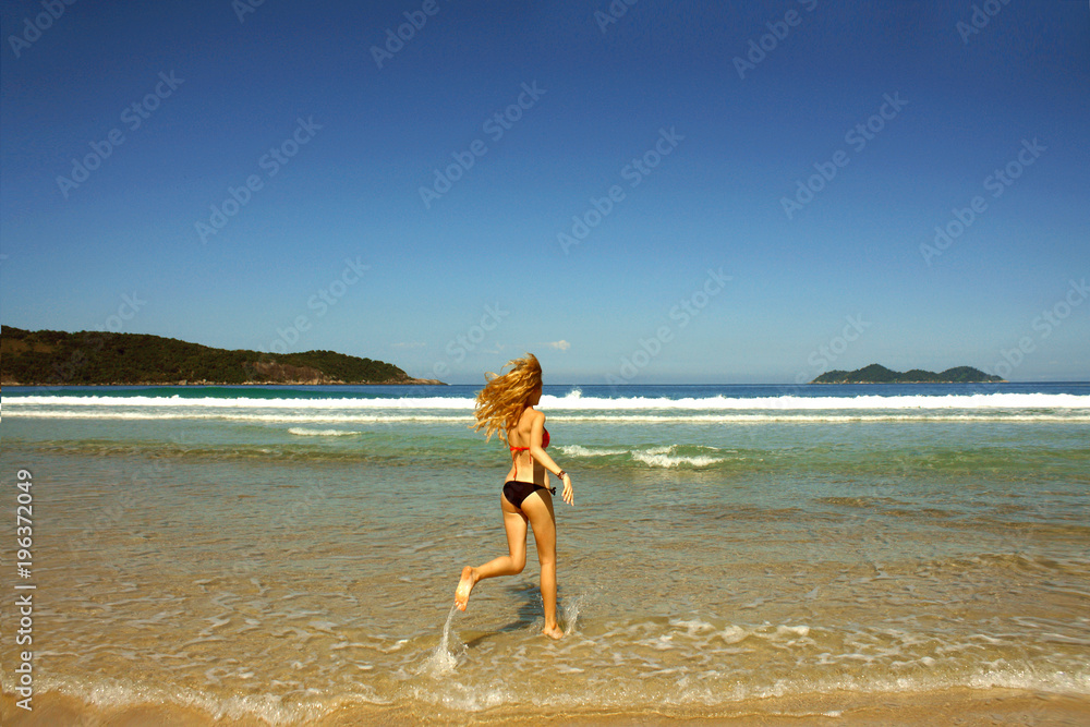 young woman in swimsuit running along the seashore, Brazil young woman in swimsuit running along the seashore, Brazil