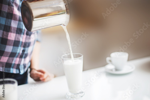 the girl is preparing morning coffee. the girl is preparing breakfast. the girl pours milk in a latte