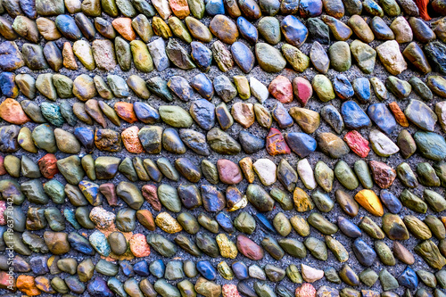 200 colourful stones lines in lines of ten in a concrete wall
