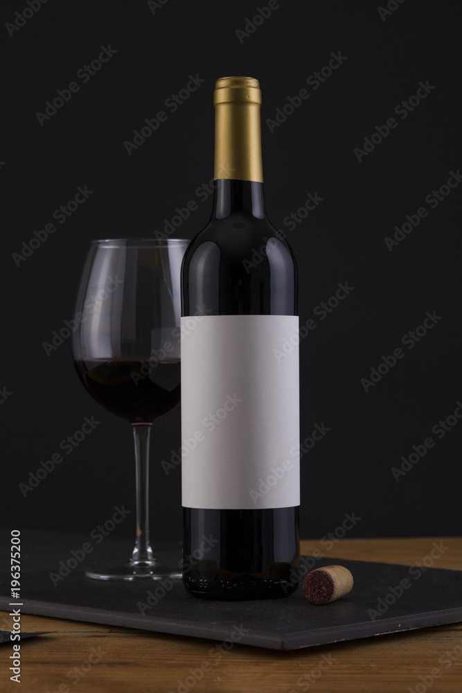 Fototapeta premium Isolated Red Wine Bottle in a Black, wood Background and White Label
