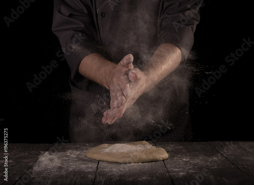 Hands of baker kneading dough isolated on black