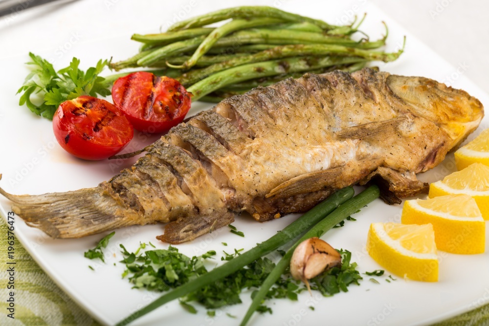 Grilled whole trout, potato, lemon and garlic, close up Grilled whole trout, potato, lemon and garlic, close up