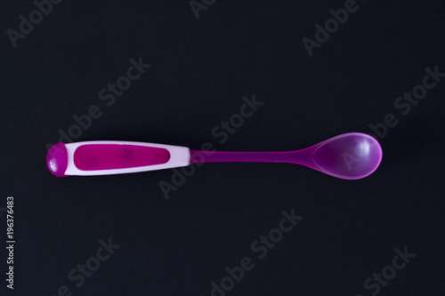 .pink baby spoon on a black background