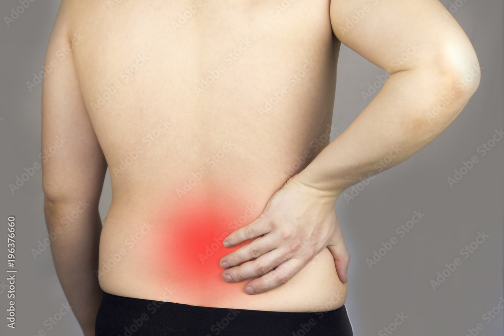 .A man holds on to his back, his back hurts, his red back, .dorsal hernia, intervertebral hernia