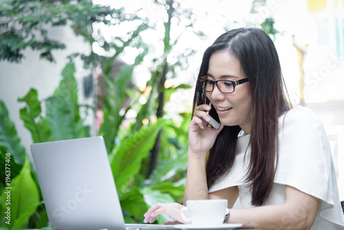 Beautiful asian attractive woman has working and talking with phone for business marketing at coffee cafe in the morning with happy and relaxing time.