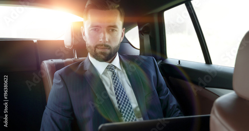 businessman with laptop sitting in a comfortable car