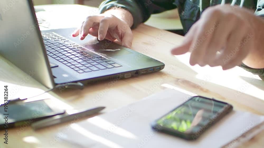 Silhouette of cropped shot of a young man working from home using smart phone and notebook computer, man's hands using smart phone in interior, man at his workplace using technology, flare light Silhouette of cropped shot of a young man working from home using smart phone and notebook computer, man's hands using smart phone in interior, man at his workplace using technology, flare light