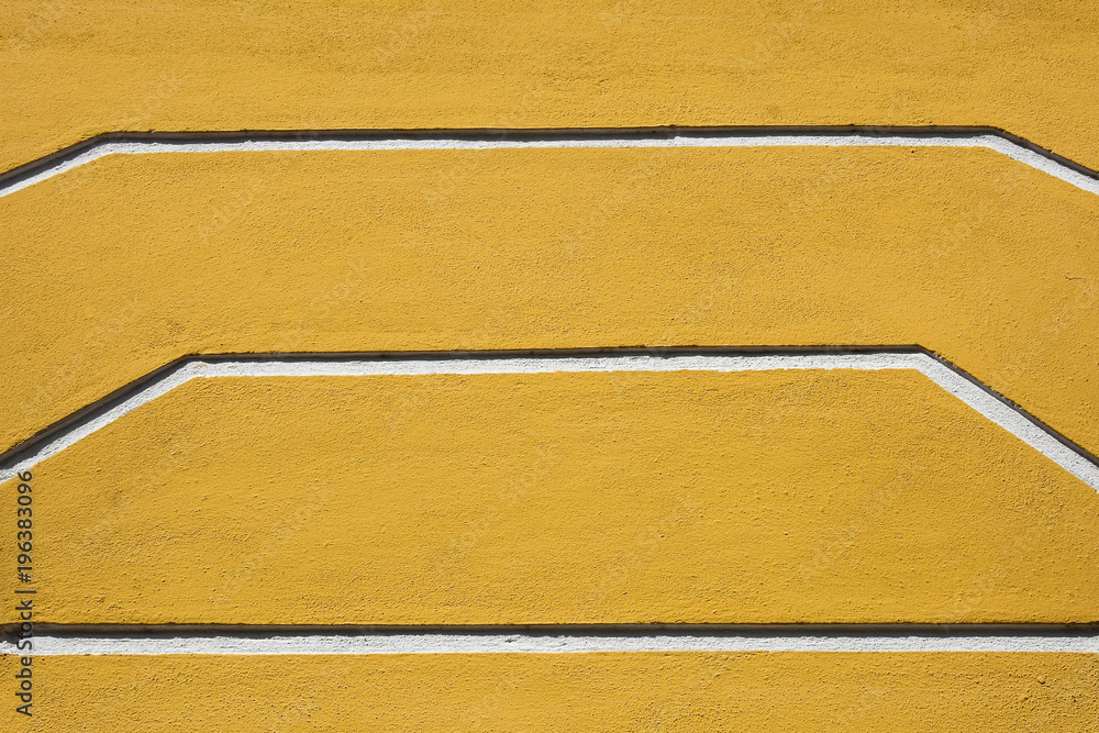 line of low relief sculpture at yellow concrete wall