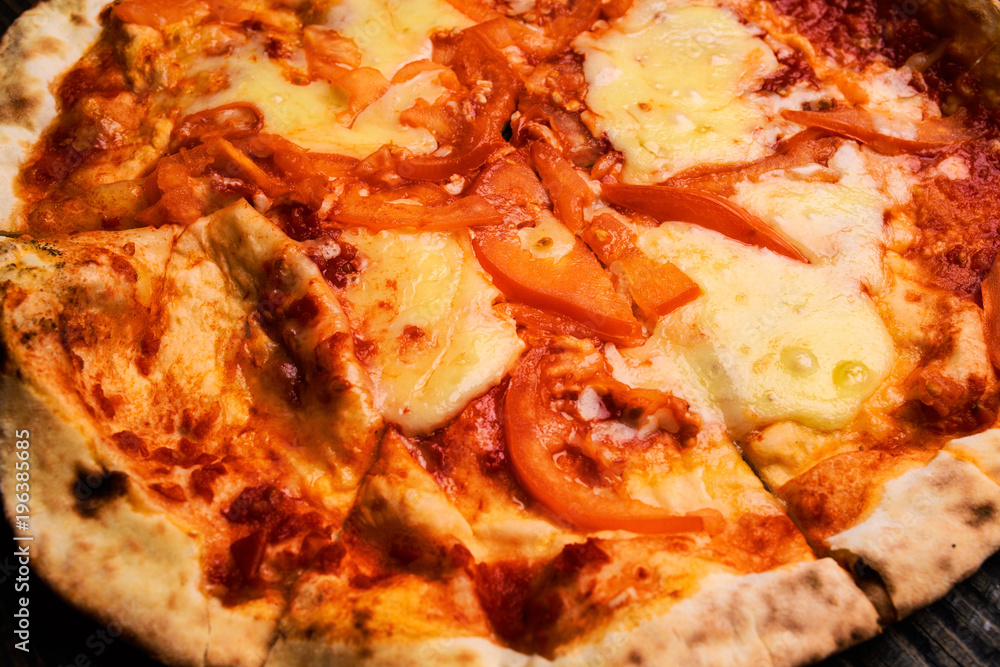 Hot pizza slice with melting cheese on a rustic wooden table. Hot pizza slice with melting cheese on a rustic wooden table.