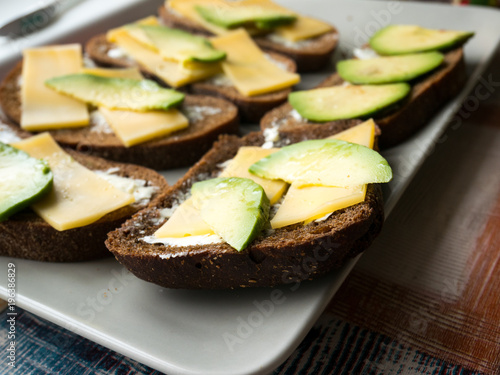 Sandwiches of avocado and cheese on black bread