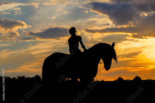 Silhouette of man riding a horse on sunset with beautiful cloudy background