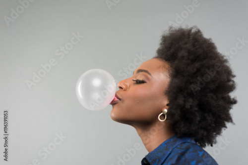Young African American Woman blowing bubble with bubble gum