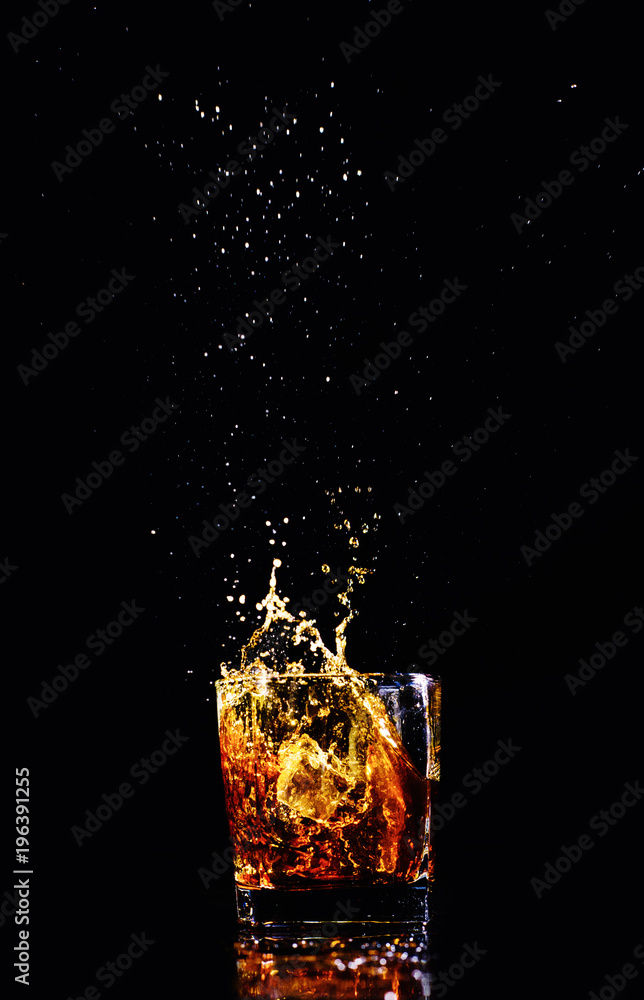 Isolated shot of whiskey with splash on black background, brandy in a glass Isolated shot of whiskey with splash on black background, brandy in a glass