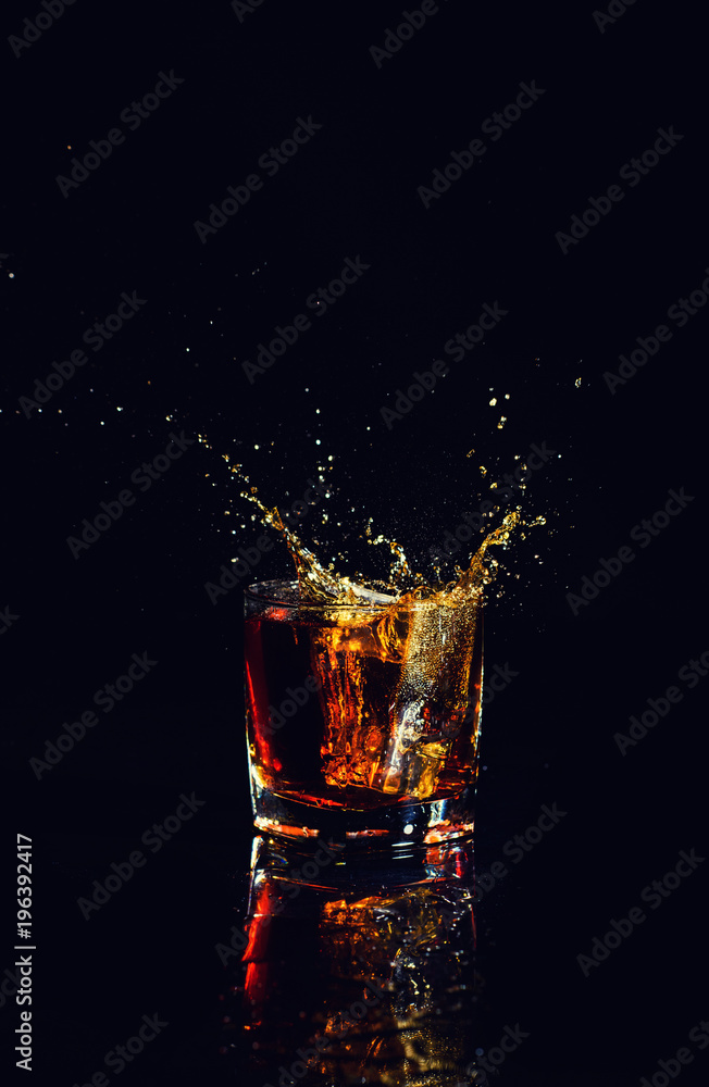Isolated shot of whiskey with splash on black background, brandy in a glass Isolated shot of whiskey with splash on black background, brandy in a glass