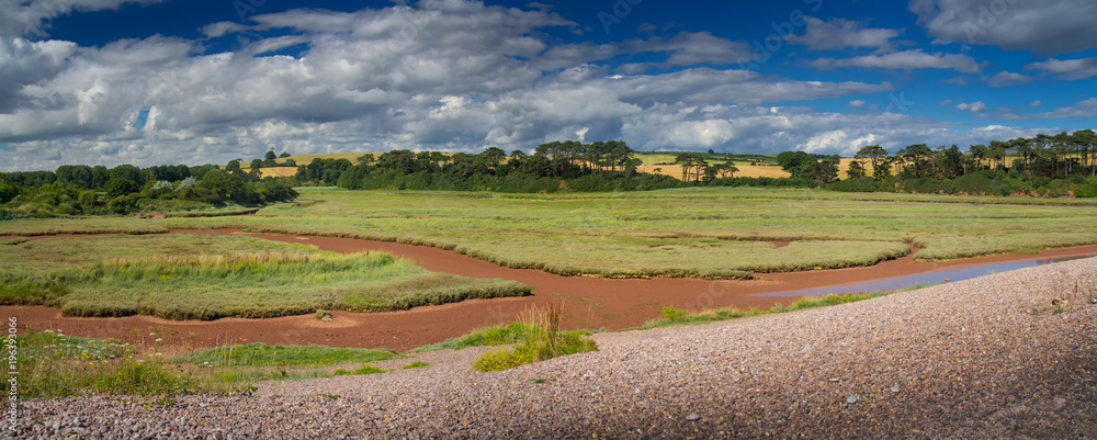 Panorama of a picturesque place on the shore of an English channel - Budleigh Salterton. Sunny summer day. Clouds in the blue sky. Devon. England