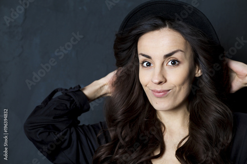 Happy tender girl. Photo of gorgeous young brunette woman  in black hipster hat