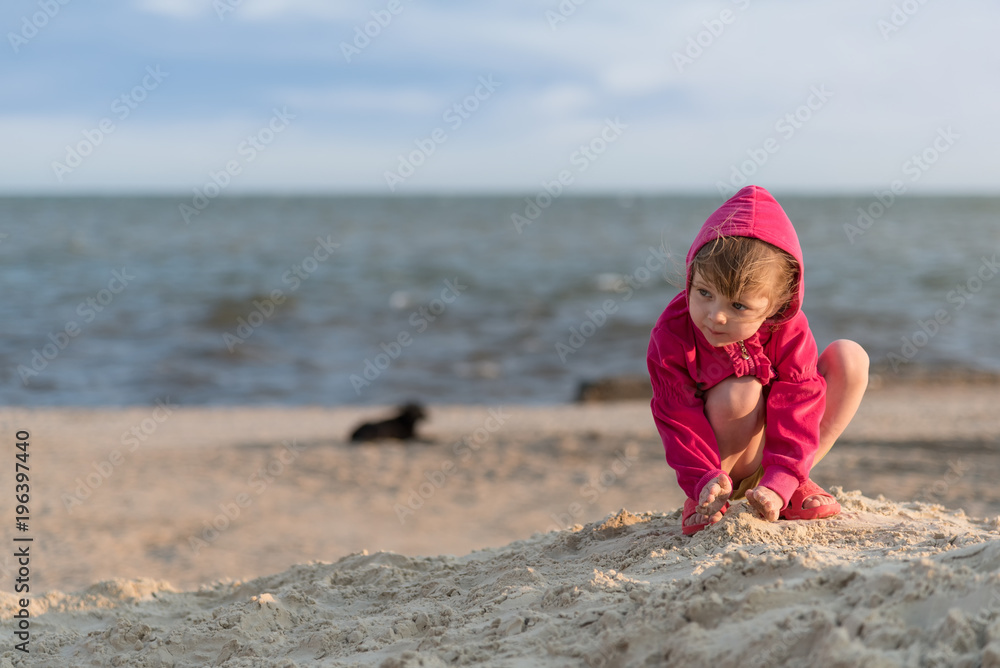 Little girl playing in the sand on the sea beach, sunset and little breeze and , summer vacation, child development, health improvement