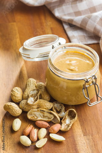 Peanut butter in jar and peanuts.