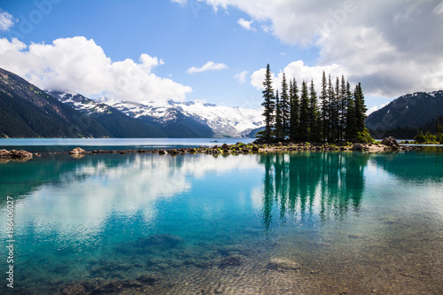 Emerald waters of Garibaldi Lake reflect bottle-green tree sihouettes