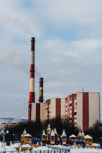 High pipes above residential buildings I release dangerous smoke near a large playground in a big city photo