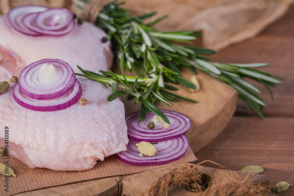 Raw chicken thighs with rosemary, red onion and peppercorns Raw chicken thighs with rosemary, red onion and peppercorns